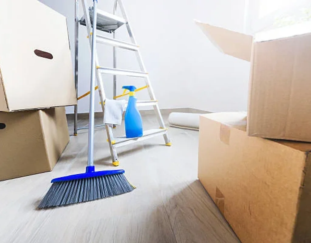 Broom, spray bottle, and moving boxes in an empty room being cleaned after a move in Apache Junction, AZ.