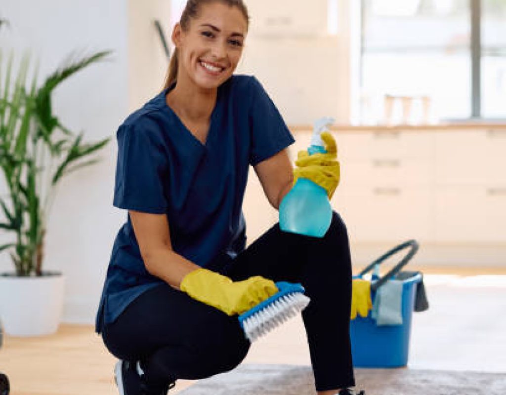 Skilled cleaner carefully vacuuming edges and dusting surfaces in upscale residence